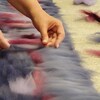 Photo où l'on voit des mains qui étendent de la laine colorée.