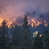 Un feu de forêt brûle près d'une maison dans la ville de Kelowna, en Colombie-Britannique, le vendredi 18 août 2023.