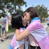 Un couple s'embrasse sur le boulevard Memorial à Winnipeg, enveloppé d'un drapeau transgenre, le 4 juin 2023. 