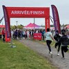 Trois coureuses approchent d'une arche rouge sur laquelle sont inscrits les mots « arrivée finish ». Une petite foule les attend.