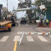 Des travailleurs installent un nouveau poteau à un coin de rue dans une ville.