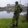 Deux militaires canadiens près de maisons endommagées.