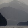 Une étendue d'eau et des montagnes plongées dans le brouillard. 