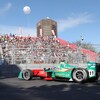 Une voiture de course électrique devant une estrade remplie.