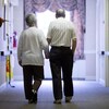 Deux personnes âgées photographiées de dos alors qu'ils marchent dans un corridor, main dans la main.