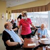 Deux aînés en train de manger. Une employée est à leurs côtés.