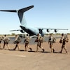 Des militaires français marchent sur le tarmac d'un aéroport où se trouve un avion.