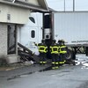 Trois pompiers examinent la cabine du camion qui se trouve dans le bâtiment.