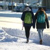 Deux jeunes filles marchent côte à côte sur un trottoir enneigé.