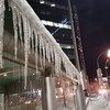 Des glaçons se sont formés au rebord d'un toit dans une rue éclairée la nuit à Winnipeg
