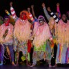 Des personnes habillées avec des vêtements très colorés dansent sur scène. 
