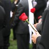 Un homme tient une rose rouge pendant des funérailles.