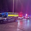 Cinq voitures de police et deux ambulances avec leurs gyrophares allumés, la nuit.
