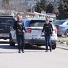 2 agents armés marchent dos à une voiture de la GRC.