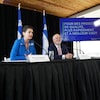Les ministres Geneviève Guilbault et Jonatan Julien assis à la table d'une conférence de presse, à côté d'un écran où on peut lire : «Pour des projets de qualité, plus rapidement et à meilleur coût».