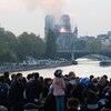 Des gens regardent la fumée s'échapper de la cathédrale Notre-Dame pendant l'incendie qui s'est déclaré le 15 avril 2019. 