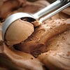 Une cuillère dans un bac de crème glacée au chocolat.