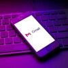 Un téléphone intelligent posé sur un clavier d'ordinateur affiche le logo de Gmail. 