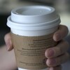 Photo d'une main qui tient un gobelet de café en carton.