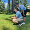 Un adolescent et un homme sont en position accroupie sur un terrain de golf.