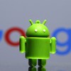 Une figurine de la mascotte du logiciel mobile Android, devant le logo de Google