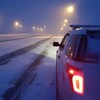 Une voiture de la GRC sur une route enneigée la nuit.