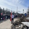 Plusieurs personnes sont debout et en écoutent une autre parler. On aperçoit le drapeau du syndicat et quelques pancartes dans la foule. 