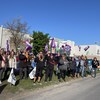 Des gens qui manifestent sur le bord de la rue, devant l'usine, avec des drapeaux de la CSN.