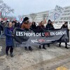 Des professeurs manifestent sur le campus de l'Université Laval. Ils portent une banderole et des pancartes. 