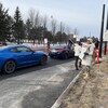 Des personnes tenant des pancartes dans une ligne de piquetage près d'une rue. 