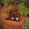 Vue aérienne de deux hommes au fond du trou d'un site de fouilles en pleine forêt.