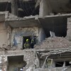 Deux secouristes circulent dans un immeuble en ruine.