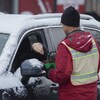 Un automobiliste donne de l'argent à un bénévole dans le cadre de la guignolée des médias.