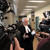 Me Guy Bertrand répond aux questions des journalistes lors d'une mêlée de presse dans les couloirs du palais de justice de Québec.
