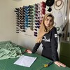 Une femme se tient dans un atelier de couture. 