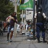 Un père court en portant son fils pendant que la police mène une opération dans une rue de Port-au-Prince.