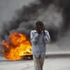 Un homme marche devant une colonne de feu dans une rue.