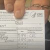 Doug Hall montre un document officiel certifiant qu'il a reçu deux doses de vaccin.