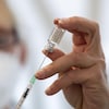 Une femme remplit une seringue à partir d'une fiole du vaccin contre la COVID-19.