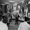 Henri Bergeron animant devant une murale. On voit la caméra et l'équipe de production en avant-plan.