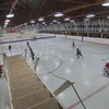 Des jeunes joueurs de hockey sur une patinoire surplombée par une passerelle