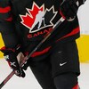 Plan rapproché du chandail de hockey noir d'Équipe Canada junior décoré du logo de Hockey Canada.