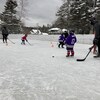 Des jeunes et des entraîneurs jouent au hockey sur une patinoire extérieure.
