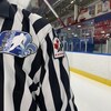 L'écusson de Hockey Québec sur l'uniforme d'un arbitre sur une patinoire.