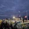 Plusieurs personnes sur le quai à l'aube devant les bateaux de pêche chargés de casiers à homard.