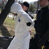 Un détenu en combinaison de plastique est escorté au palais de justice par deux policiers.