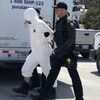 Un détenu en combinaison de plastique arrive au palais de justice escorté par deux policiers.