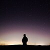Une personne regarde l'horizon dans une nuit étoilée.