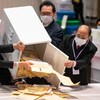 Des hommes vident une urne contenant des bulletins de vote