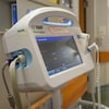 Un appareil d'équipement médical avec un écran rangé le long du mur dans le corridor d'un hôpital.